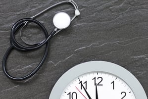 Stethoscope and a clock laying next to each other.
