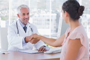 Smiling doctor shaking hands with patient