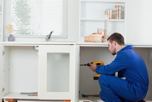 Man using a drill to install a cabinet