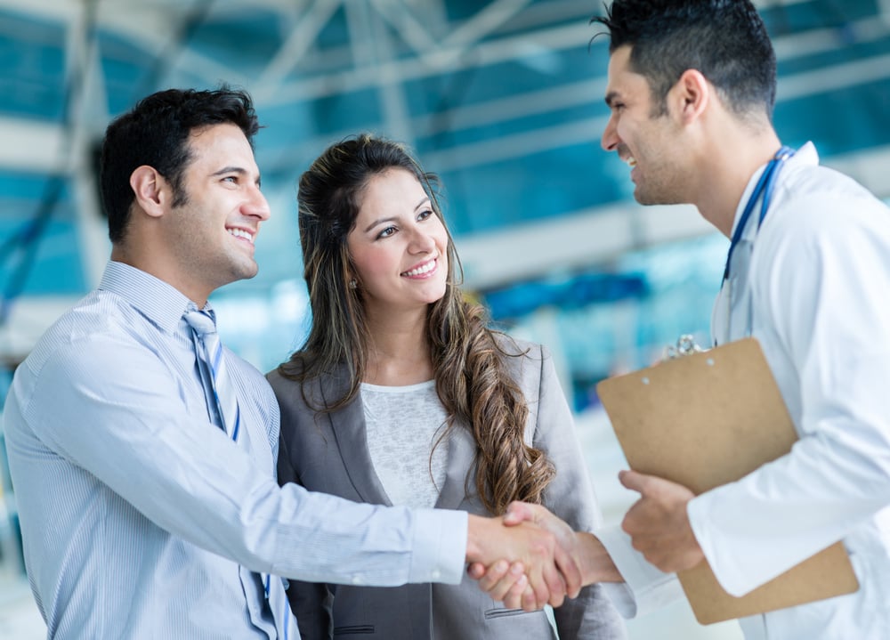 Smiling couple shaking hands with provider