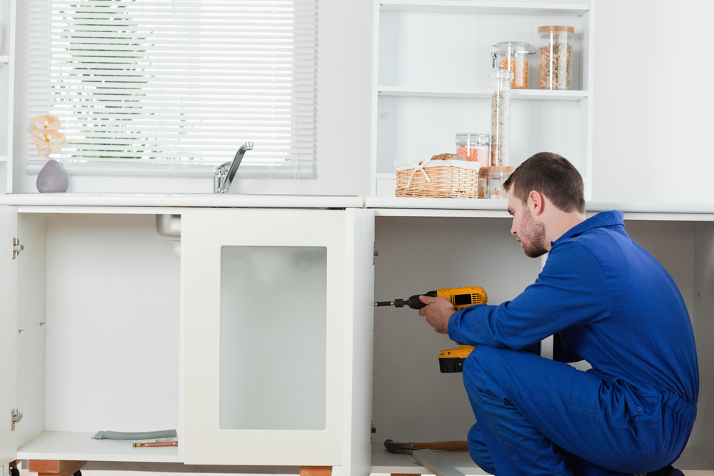 Man using a drill to install a cabinet